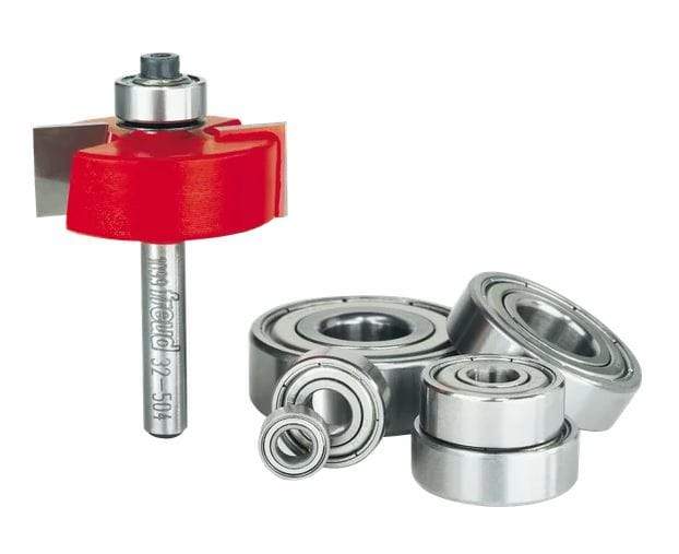 An industrial router bit with a red body and a bearing on top is standing upright on the left side of the frame. To the right of the router bit is a cluster of different sizes of metal bearings.