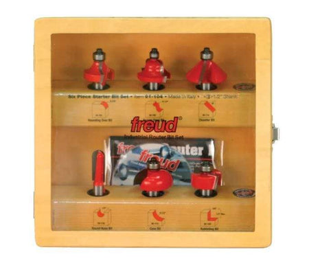 Image of entire bit set. This is a wooden case containing a six-piece Freud industrial router bit set. The bits have silver shanks and red cutting heads, and the case also includes diagrams illustrating the cutting profiles of each bit.