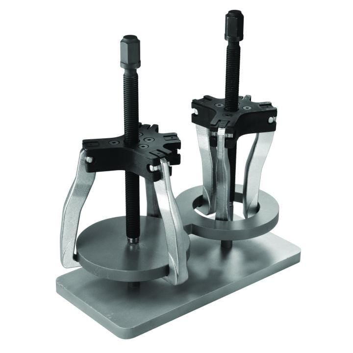 Image of GearWrench 2 & 5 Ton 2 or 3 Jaw Internal/External Ratcheting Puller Set. The image shows two silver and black mechanical pullers, tools used for removing parts, standing on a flat metal base. Each tool has a central threaded rod and three curved jaws that grip a circular plate, creating a setup for applying force to remove a part.